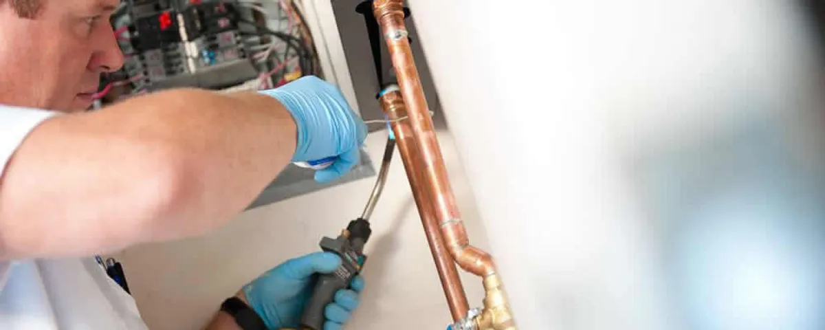 Water heater repair technician testing copper pipe connections and controls in Lancaster, PA
